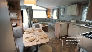 een keuken en een woonkamer met een tafel en een bank bij 9 The Meadows FallBarrow Park in Bowness-on-Windermere