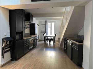 a kitchen with black cabinets and a table with chairs at Chez Camille et David in Sorgues