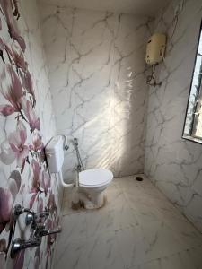 a bathroom with a toilet and a marble wall at Green Vista Villa in Trimbak