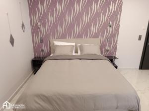 um quarto com uma cama branca e uma parede roxa em Modern studio in the city center em Chalkida