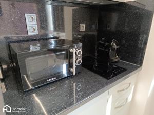 a black counter top with a microwave in a kitchen at Modern studio in the city center in Chalkida
