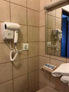 ein Bad mit einem Telefon und einem Spiegel in der Unterkunft Hotel Am Flughafen in Köln