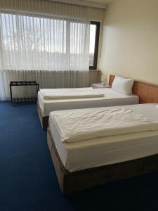 3 camas en una habitación de hotel con ventana en Hotel Am Flughafen en Colonia