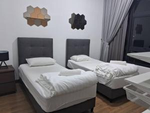 twee bedden in een kamer met witte muren bij Astoria Ampang by Riche Realty in Kuala Lumpur