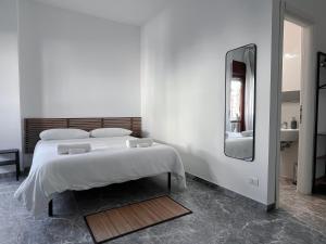 a white bedroom with a bed and a mirror at Pascià Rooms in Rome