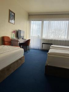a hotel room with two beds and a desk at Hotel Am Flughafen in Cologne