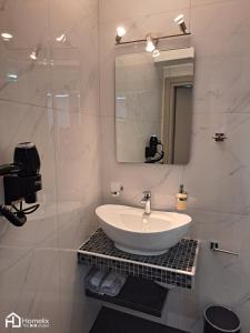 a white bathroom with a sink and a mirror at Modern studio in the city center in Chalkida