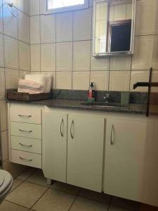 a white bathroom with a sink and a toilet at 3 Quartos da UFU in Uberlândia