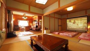 una sala de estar con 2 camas y una pantalla grande en お湯掛け流し『草津温泉湯畑』徒歩圏内※温泉街を大勢で遊びたい & 癒されたい en Kusatsu