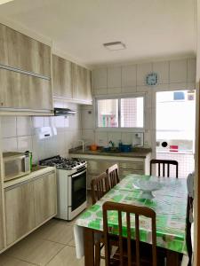 uma cozinha com uma mesa e um fogão forno superior em Apartamento Ubatuba-Itaguá em Ubatuba