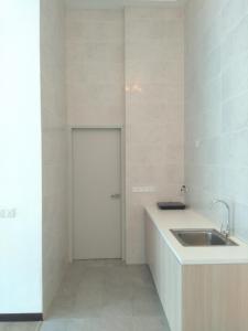 eine weiße Küche mit einem Waschbecken und einer Tür in der Unterkunft Sann's Lodge in Putrajaya