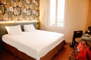 a bedroom with a large white bed with a flowered wall at Hôtel de France Vire in Vire