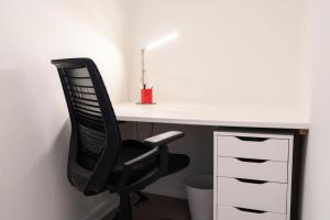 a desk with a black chair and a white desk at Heights of Kortrijk in Kortrijk