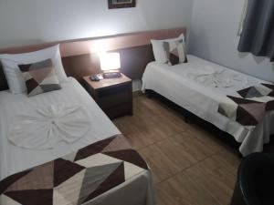 um quarto de hotel com duas camas e uma mesa com um candeeiro em Hotel Ype de São Carlos em São Carlos