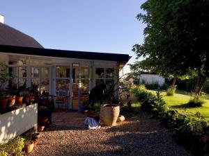 a house with a conservatory with potted plants in the yard at pallisgaard B&B in Struer