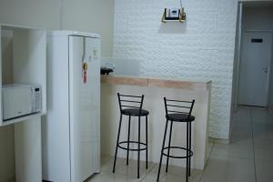 a kitchen with two bar stools and a refrigerator at Hospedaria Valdice Damasceno Centro Histórico in Piranhas