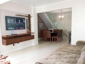 a living room with a television and a dining room at Linda Cobertura duplex compartilhada a duas quadras do mar in Itapema