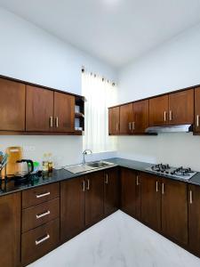 a large kitchen with wooden cabinets and a sink at Shan Stay in Moratuwa