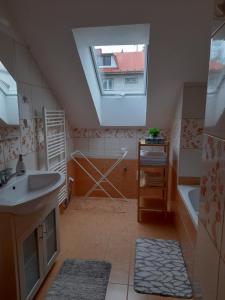 uma casa de banho com um lavatório, uma banheira e uma janela em Apartmán u potoka em Nové Město na Moravě