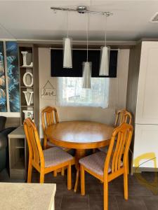 een eetkamer met een houten tafel en stoelen bij Highfield Grange Caravan Park (Parkdean) in Little Clacton