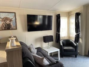 a living room with a couch and a bull on the wall at Highfield Grange Caravan Park (Parkdean) in Little Clacton