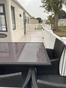 a table and chairs on a patio with a house at Highfield Grange Caravan Park (Parkdean) in Little Clacton