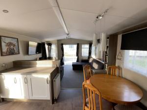 cocina y zona de comedor de una cabaña con mesa en Highfield Grange Caravan Park (Parkdean) en Little Clacton