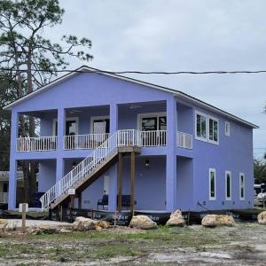 ein blaues Haus mit einer Veranda und einem Balkon in der Unterkunft Humpback Whale - New House View of Imperial River- 1.5 Mi 2 Beach in Bonita Springs