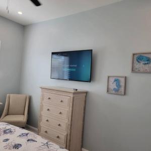 ein Schlafzimmer mit einer Kommode und einem Flachbild-TV an der Wand in der Unterkunft Humpback Whale - New House View of Imperial River- 1.5 Mi 2 Beach in Bonita Springs
