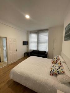 ein weißes Schlafzimmer mit einem Bett und einer Couch in der Unterkunft Garnet - Deluxe London Studio in South Norwood