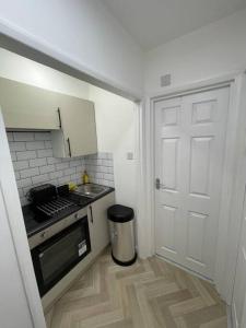 eine kleine Küche mit einem Waschbecken und einer Tür in der Unterkunft Garnet - Deluxe London Studio in South Norwood