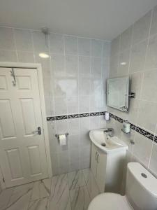 ein Badezimmer mit weißer Toilette und Waschbecken in der Unterkunft Garnet - Deluxe London Studio in South Norwood