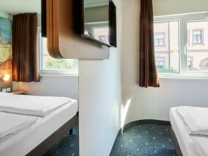 um quarto com duas camas e duas janelas em B&B Hotel Würzburg em Würzburg