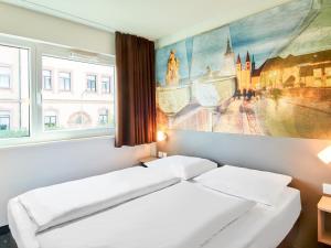 ヴュルツブルクにあるB&B Hotel Würzburgのベッドルーム1室(ベッド2台付)が備わります。壁には絵画が飾られています。