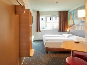 ヴュルツブルクにあるB&B Hotel Würzburgのベッド2台とテーブルが備わるホテルルームです。