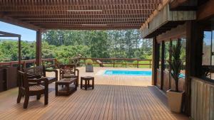 a large deck with chairs and a swimming pool at Rancho 3 Guri in Osório