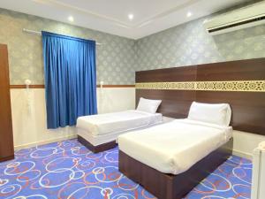a bedroom with two beds and a blue curtain at Negmat Sedqy Makkah in Makkah