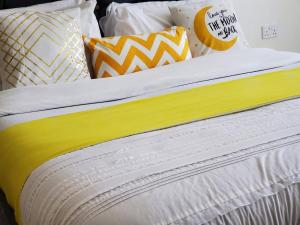 een bed met gele en witte lakens en kussens bij Shyrah Havana in Nairobi