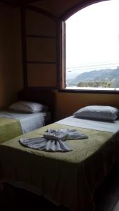 two beds in a room with a towel on the bed at hostel MdeMarilia in Nova Friburgo