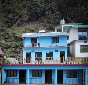 a blue and white house with a balcony at King of Himalaya Homestay in Sari