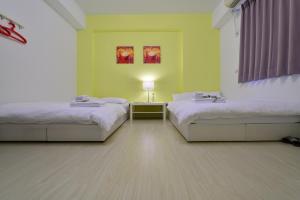 a room with two beds and a table with a lamp at STSP Guest House in Xinshi