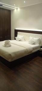 um quarto com uma cama grande e almofadas brancas em Hotel JVW Arena em Motīhāri