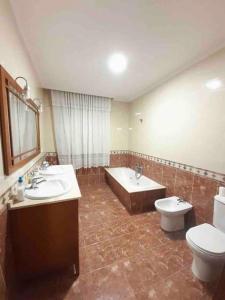 une salle de bain avec deux lavabos et une baignoire et des toilettes dans l'établissement Acogedora casa cerca de Marín, à Pontevedra