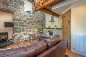 a living room with a leather couch and a stone wall at Ty-Gwair-Byrdir in Dyffryn