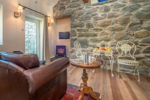 a living room with a couch and a stone wall at Ty-Gwair-Byrdir in Dyffryn