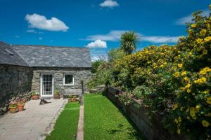 una casa de piedra con un jardín con perros en el patio en Ty-Gwair-Byrdir, en Dyffryn