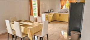 a kitchen with a wooden table and white chairs at Kapowlito Real Estate Casa #2 Mon Plaisirweg in Paramaribo