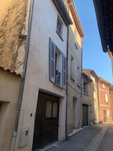 een steeg met een gebouw met een deur en een balkon bij L isle aux Rêves appartement plain-pied avec patio RDC in LʼIsle-sur-la-Sorgue