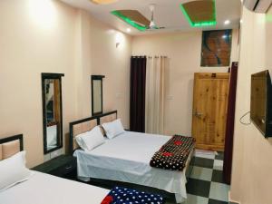 a bedroom with two beds and a tv in it at Mishra Guesthouse in Varanasi