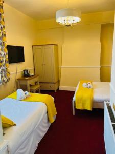 a hotel room with two beds and a tv at Crown Hotel Brackley in Brackley